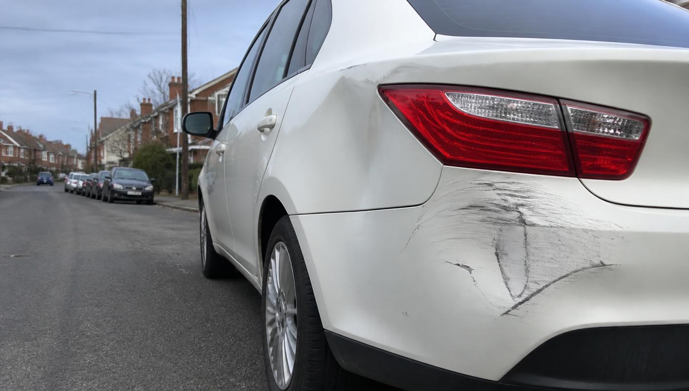 Damaged rear panel of a parked car on a residential street
